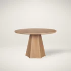 Round natural wood dining table with sculptural pedestal base.
