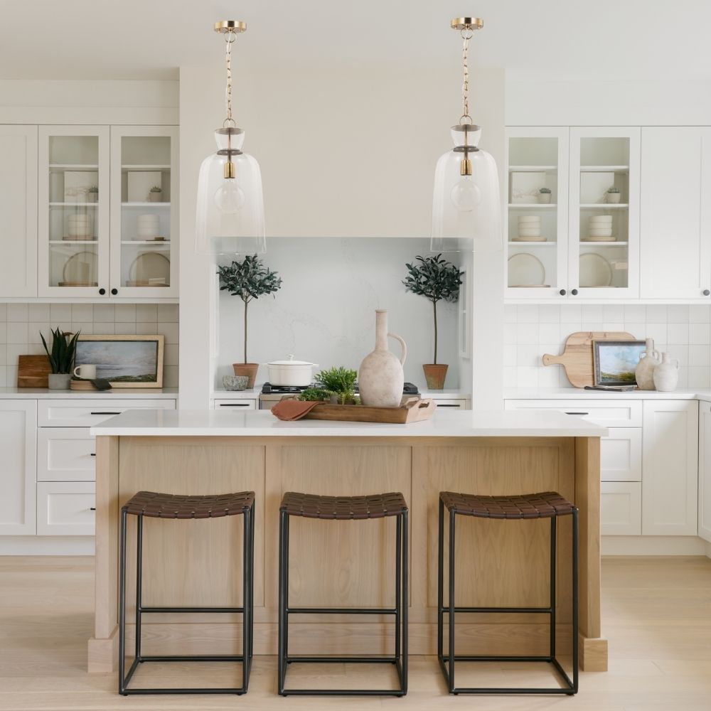 Tall clear glass pendant light with gold metal hardware and a single exposed bulb, suspended from a matching gold chain.
