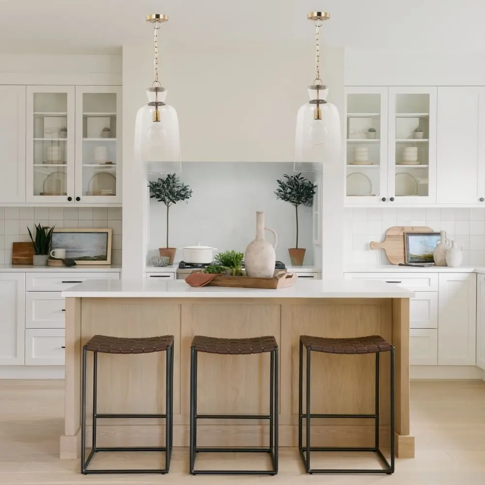 Tall clear glass pendant light with gold metal hardware and a single exposed bulb, suspended from a matching gold chain.