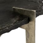 Irregular black stone coffee table with a jagged, organic edge and industrial hammered metal base.