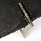 Irregular black stone coffee table with a jagged, organic edge and industrial hammered metal base.