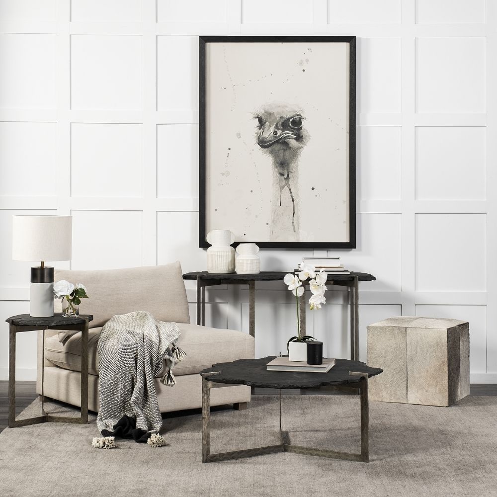 Irregular black stone coffee table with a jagged, organic edge and industrial hammered metal base.
