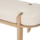 Light oak bench with rounded upholstered cushion in soft neutral fabric.