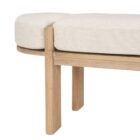 Light oak bench with rounded upholstered cushion in soft neutral fabric.