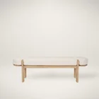 Light oak bench with rounded upholstered cushion in soft neutral fabric.