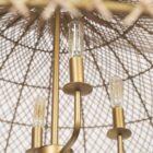Large dome-shaped chandelier featuring a woven rattan-style metal frame with gold finish and inner candelabra-style bulbs.
