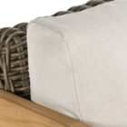 Outdoor lounge chair with white cushions, woven wicker frame, and teak wood arms.