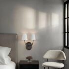 Double-arm wall sconce with white tapered shades and oil-rubbed bronze finish.
