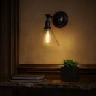 Vintage-style wall sconce with clear glass cone shade and matte black base.
