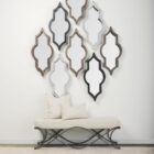 A bold, arched Mercana Tamanar Mirror featuring a striking black frame with structured lines, leaning stylishly against a neutral-toned wall.
