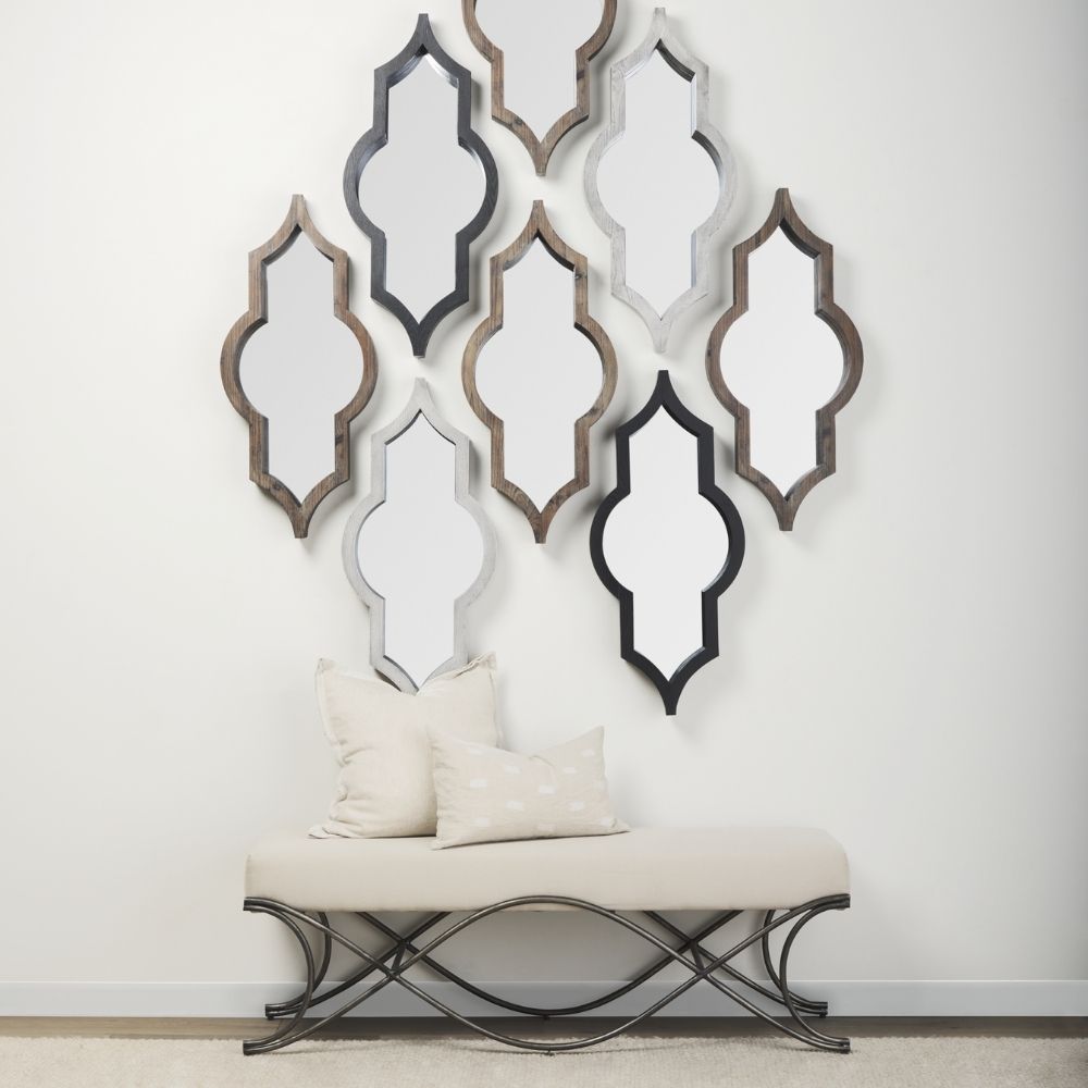 A bold, arched Mercana Tamanar Mirror featuring a striking black frame with structured lines, leaning stylishly against a neutral-toned wall.
