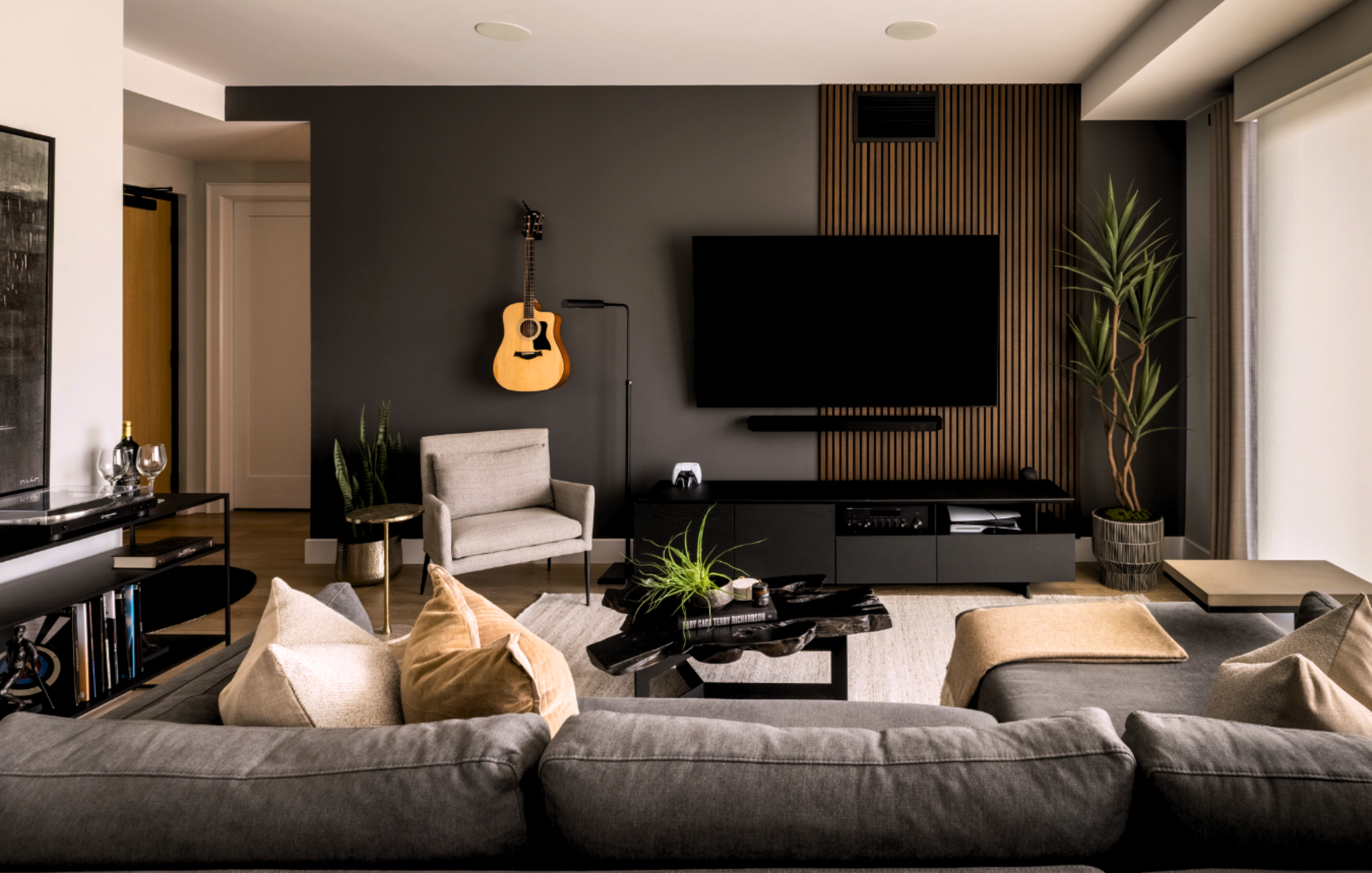 Contemporary media room with dark feature wall, mounted TV, and guitar decor.