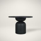 Modern round black dining table with sculptural pedestal base and smooth wood finish.