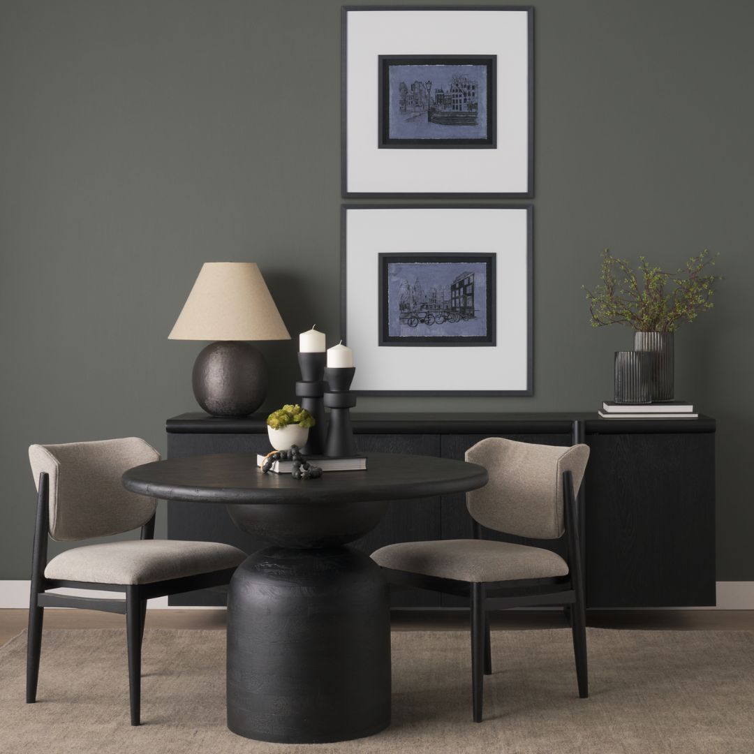 Modern round black dining table with sculptural pedestal base and smooth wood finish.