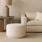 Renwil Audrina Ottoman with round silhouette upholstered in soft white textured fabric.