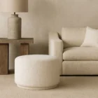 Renwil Audrina Ottoman with round silhouette upholstered in soft white textured fabric.
