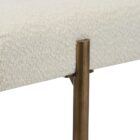 A minimalist upholstered bench in ivory boucle fabric with slim antique brass-finished tapered legs.