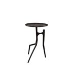 A sculptural black metal side table with a round top and organic tripod-style base featuring asymmetrical, branch-like legs.