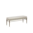 A modern upholstered bench with a slim ivory cushion and sleek antique brass-finished metal frame with tapered legs