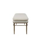 A modern upholstered bench with a slim ivory cushion and sleek antique brass-finished metal frame with tapered legs