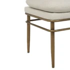 A modern upholstered bench with a slim ivory cushion and sleek antique brass-finished metal frame with tapered legs