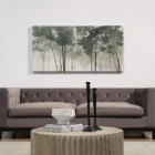A nature-inspired wall art piece depicting tall trees with dark green foliage fading into a misty, neutral-toned background.