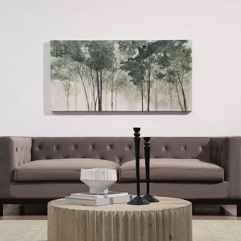 A nature-inspired wall art piece depicting tall trees with dark green foliage fading into a misty, neutral-toned background.