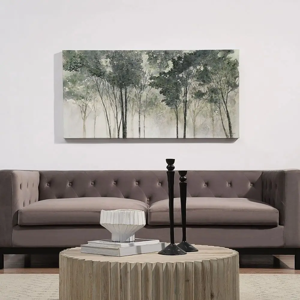 A nature-inspired wall art piece depicting tall trees with dark green foliage fading into a misty, neutral-toned background.
