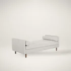Contemporary upholstered bench with tufted seat, bolster cushions, and wooden legs in soft light fabric.