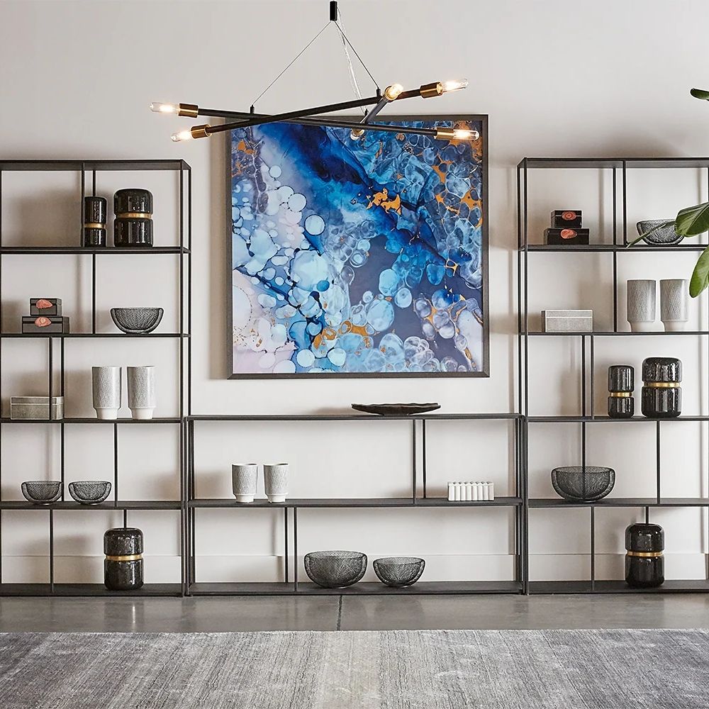 Tall narrow bookcase with slim gold metal frame and staggered open shelving.