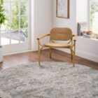 Traditional area rug with a distressed medallion pattern in soft grey, ivory, and muted blue tones.