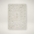 Neutral traditional rug in soft beige and cream with an all-over floral pattern and subtle distressed detailing.