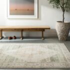 Vintage-inspired woven rug with a faded diamond medallion in muted green, ivory, and blush tones.