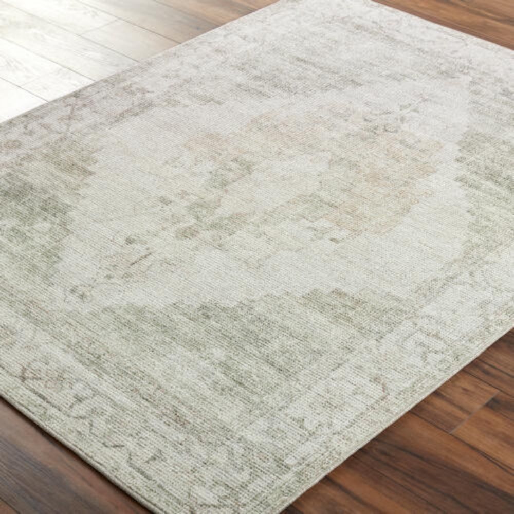 Vintage-inspired woven rug with a faded diamond medallion in muted green, ivory, and blush tones.