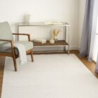 Beige and ivory machine woven rug with a soft medallion and distressed traditional pattern.