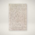 Neutral woven rug with a subtle distressed floral medallion pattern in beige and ivory tones.