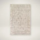 Neutral woven rug with a subtle distressed floral medallion pattern in beige and ivory tones.