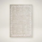 Beige and ivory rug with subtle floral motifs and a delicate bordered pattern.