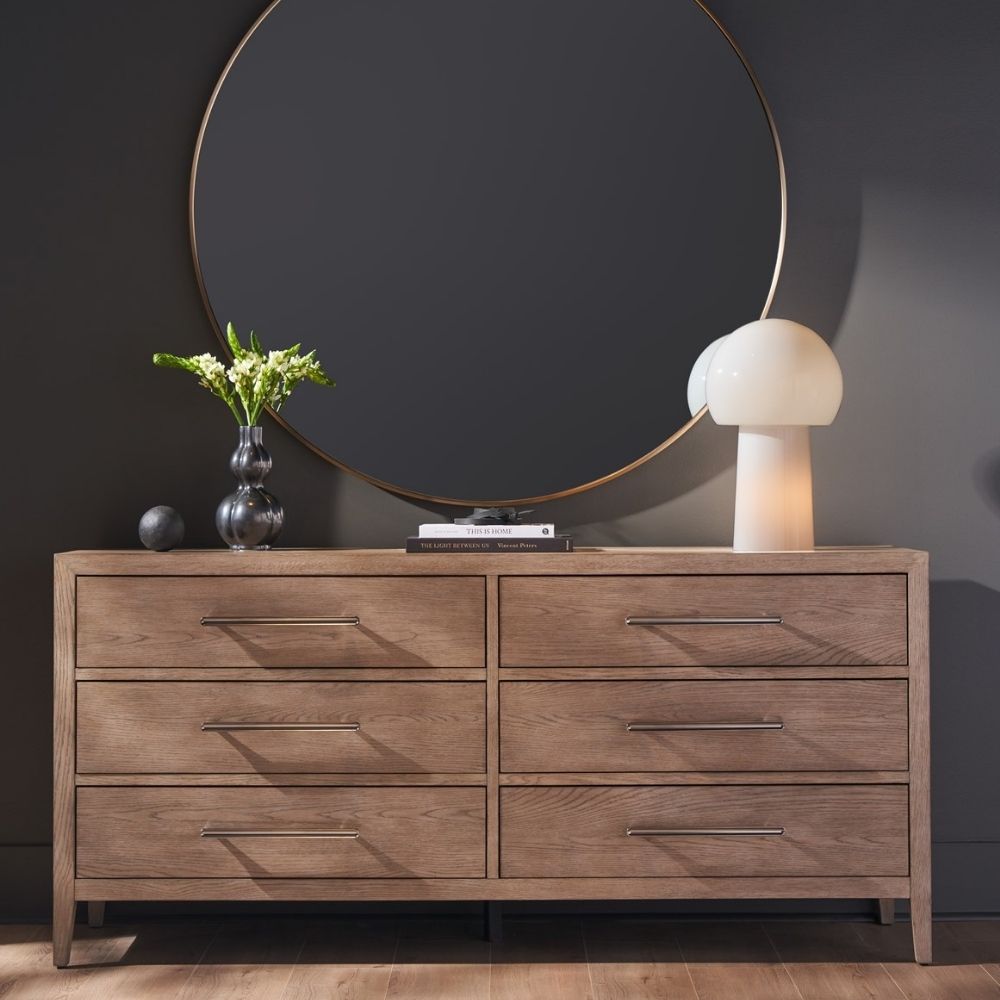 A six-drawer dresser in a light natural wood finish with long horizontal metal handles and tapered legs.