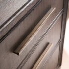 A four-drawer chest in a dark textured wood finish with elongated brass handles and slim tapered legs.