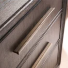 A four-drawer chest in a dark textured wood finish with elongated brass handles and slim tapered legs.