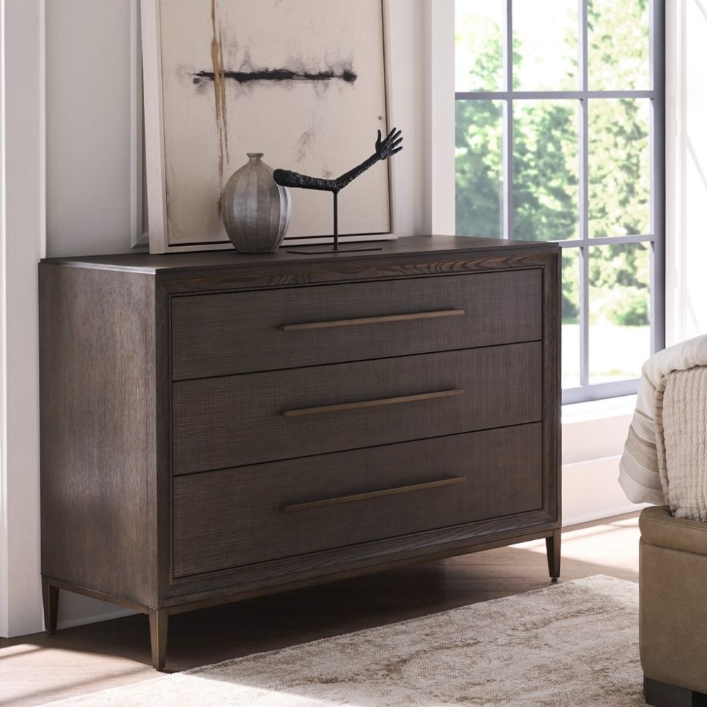 A four-drawer chest in a dark textured wood finish with elongated brass handles and slim tapered legs.