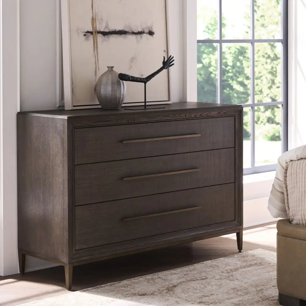 A four-drawer chest in a dark textured wood finish with elongated brass handles and slim tapered legs.
