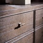 A nine-drawer dresser in a rich cocoa brown wood finish with textured grain, slim brass hardware, and tapered legs.