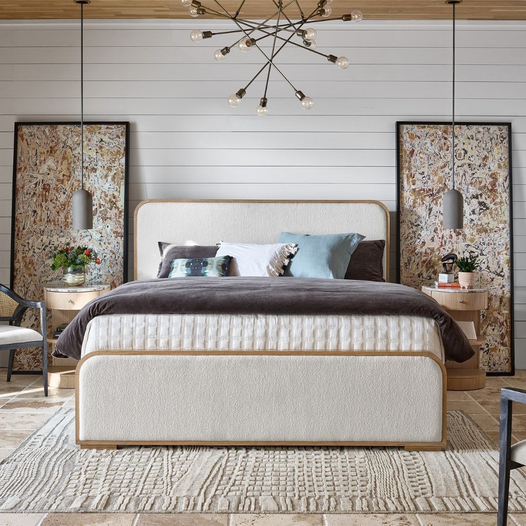A contemporary upholstered bed with soft cream fabric panels framed by light natural wood, featuring rounded corners and a modern profile.