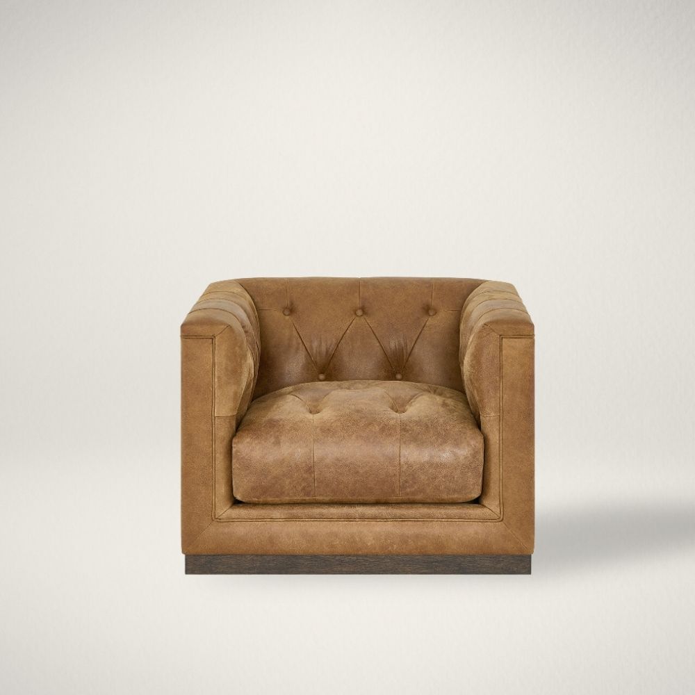 UN QUINN SWIVEL CHAIR L Square tufted leather swivel chair with deep seat and modern silhouette.