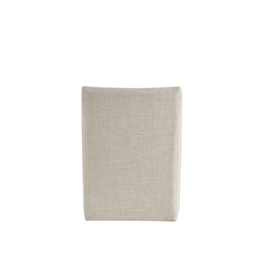 Contemporary upholstered dining chair in soft neutral fabric with clean lines, low arms, and a fully skirted base.