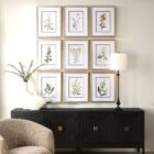 Set of nine framed botanical prints featuring colorful floral illustrations with green leaves and stems on white backgrounds, each in a light wood frame.