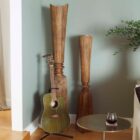 Tall handcrafted wooden sculpture with natural grain and geometric carved detailing.