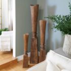 Tall handcrafted wooden sculpture with natural grain and geometric carved detailing.